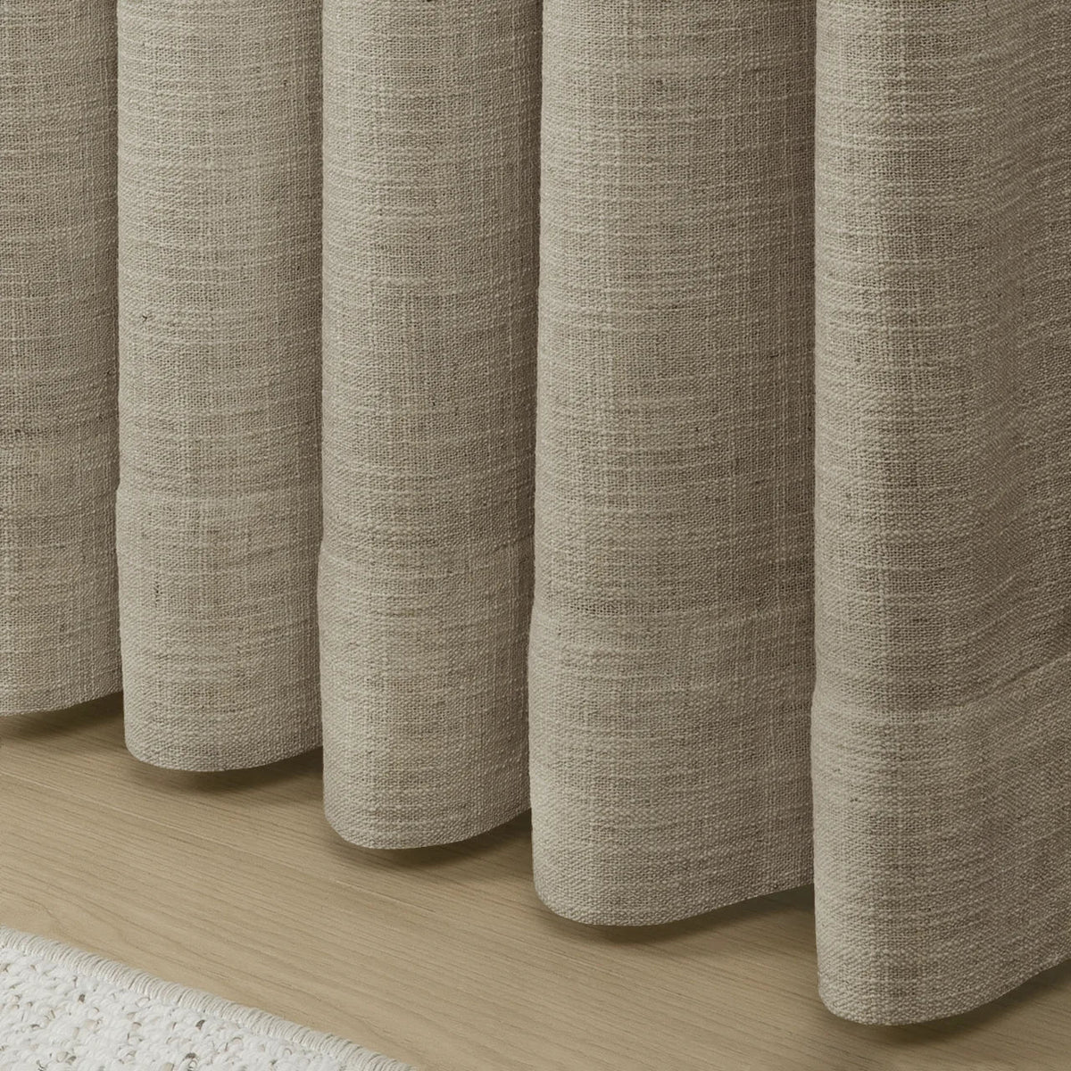 Grey Beige Liz Linen Pleated Curtains rounded curtain hems above a pale wood floor